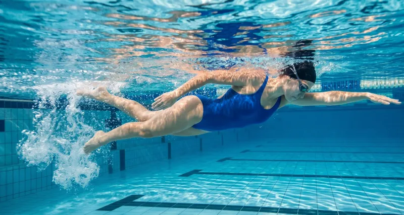 Schwimmerin beim Kraulen unter Wasser im Hallenbad